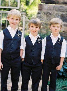 three young boys wearing black vests and white shirts