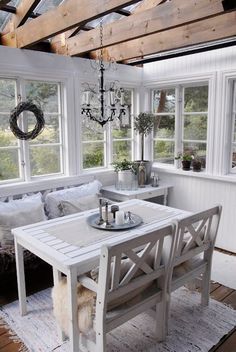 a white table sitting in the middle of a living room next to a couch and window