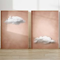 two framed pictures with clouds on them in an empty room, one is pink and the other is white