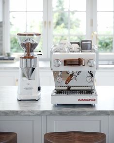 an espresso machine sitting on top of a counter next to another coffee maker