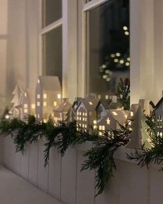 a window sill decorated with christmas lights and greenery in front of a house