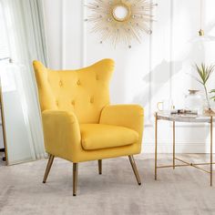 a yellow chair sitting in a living room next to a table with a plant on it