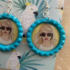 a pair of blue earrings with a picture of a woman in sunglasses on the front