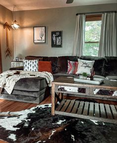 a living room filled with furniture and a cowhide rug on the floor in front of a window