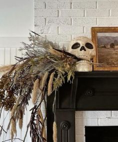 a skull sitting on top of a mantle next to a fire place with dried plants