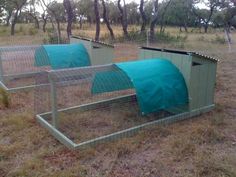 three chicken coops with blue covers on them in the middle of an open field