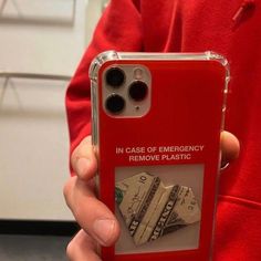 a person holding a red case with money on it and the words in case of emergency remove plastic