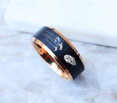 a black and gold wedding band with an image of trees on the inside of it