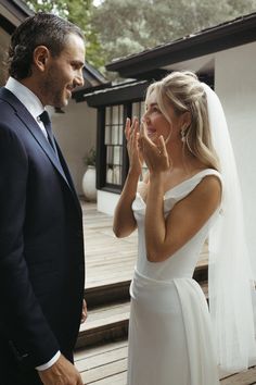 a bride and groom are standing on the steps outside their house, smiling at each other