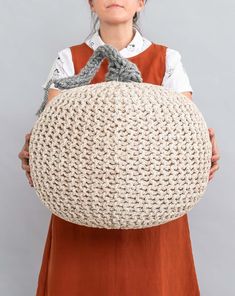 a woman in an orange dress is holding a large crocheted bag with handles