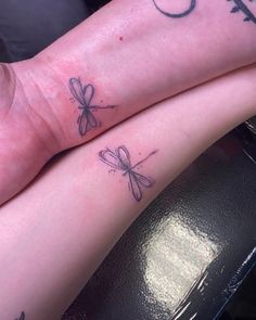 two tattoos on the legs of people sitting next to each other, one has a dragonfly