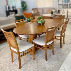 a wooden table with chairs around it in a room filled with couches and tables