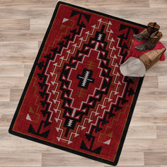 a red rug with black and white designs next to some shoes on the wooden floor