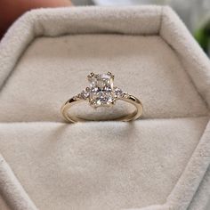 an engagement ring with three stones in it sitting inside a velvet box on top of a table