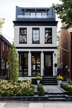 a black and white house with stairs leading up to the front door, surrounded by landscaping