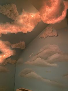 clouds painted on the wall and ceiling in a child's room with lights coming from them