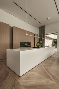 a modern kitchen with wooden floors and white counter tops, along with an island in the middle