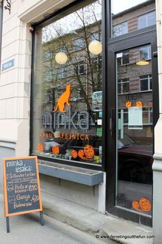 an orange sign is in front of a store window that has pumpkins on it