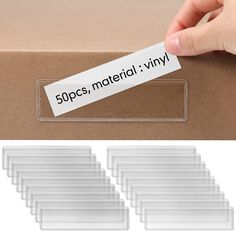 a hand holding a sticker that says 50pss, material vinyl on top of a cardboard box