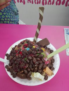 a white plate topped with lots of chocolate covered beans and marshmallows next to a straw