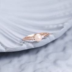 a ring with two pearls on it sitting on a white cloth covered tablecloth,