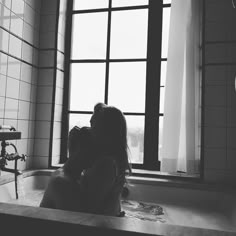 two women are sitting in the bathtub with their backs to each other and looking out the window