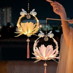 a person holding a cell phone in front of a wind chime with flowers on it