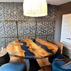 a wooden table sitting next to two blue chairs in front of a wall with rocks on it