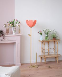 a living room with pink walls and flowers on the table, next to a gold plant stand