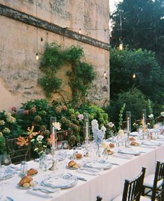 a long table is set up with plates and silverware for an outdoor dinner party