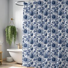 a blue and white shower curtain next to a bathtub in a bathroom with wooden floors