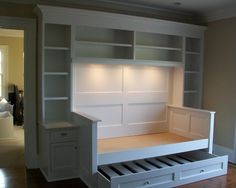 an empty room with built in bookshelves and drawers on the bottom shelf,