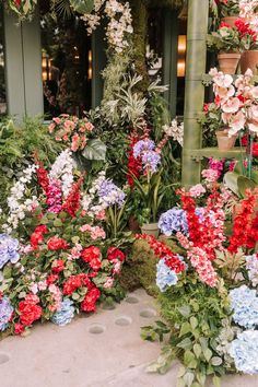 many different colored flowers are growing in the planter area at the entrance to a building