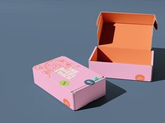 an open pink box sitting on top of a blue surface next to a cardboard box