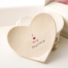 a heart shaped dish with the words i love my mommy written on it next to a stack of plates