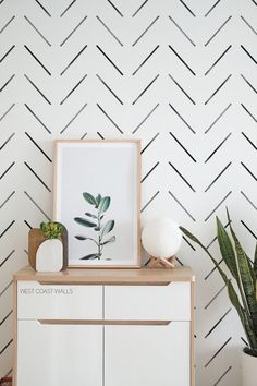 a white cabinet sitting next to a potted plant on top of a wooden table