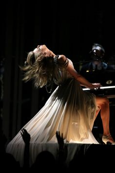 a woman in a white dress is playing the piano