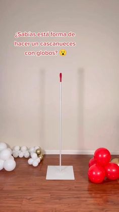 balloons are arranged on the floor in front of a white pole with a red stick sticking out of it