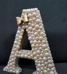 a letter made out of pearls with a bow on the top and bottom part of it