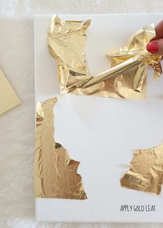 someone is painting gold foil on a piece of white paper with scissors and some glue