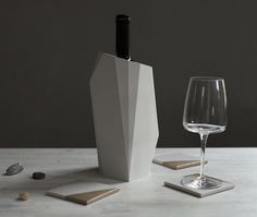 a wine glass sitting next to a white vase on top of a wooden table with rocks