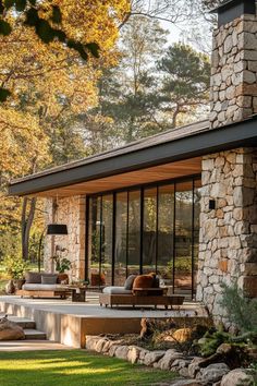 an outdoor living area with stone walls and large windows