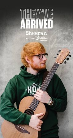 a man with red hair and glasses holding an acoustic guitar