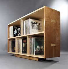 a wooden book shelf filled with lots of books on top of grey flooring next to a gray wall