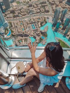 a woman sitting on top of a building looking down at the city from inside it