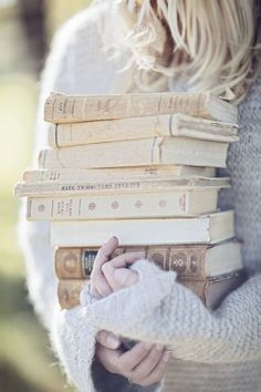 a woman holding a stack of books in her hands