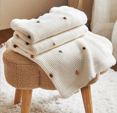 a pile of blankets sitting on top of a wooden stool