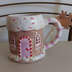 a ceramic mug with a gingerbread house on the inside and candy canes in the outside