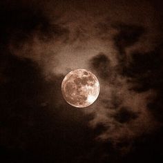 the full moon shines brightly in the night sky with clouds and dark skies behind it