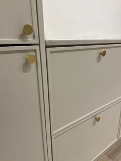 two white cabinets with brass handles and knobs